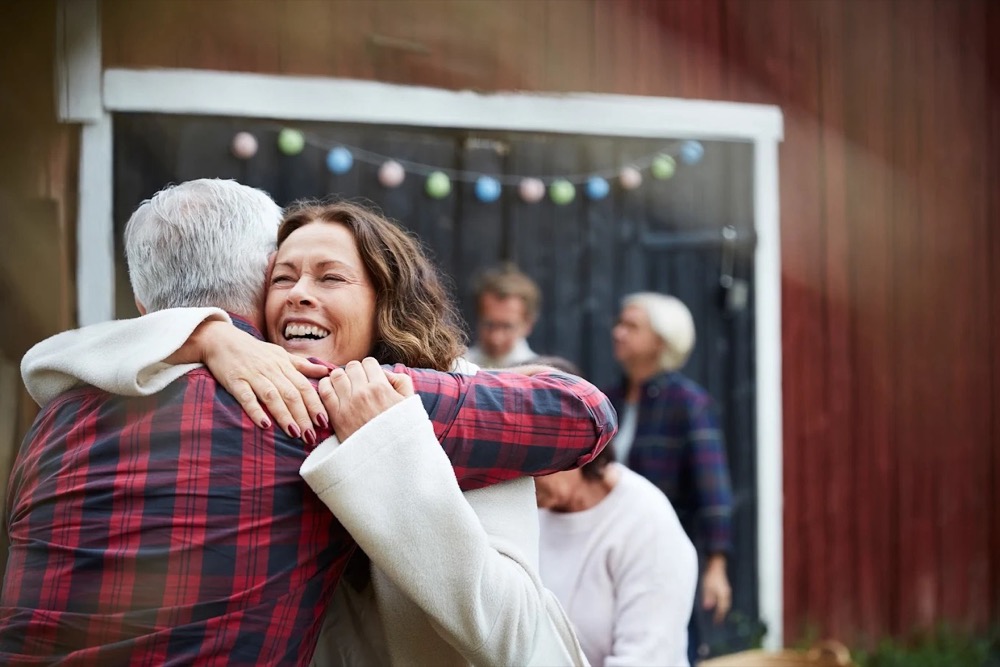 An older man and his adult daughter hugging at a family gathering