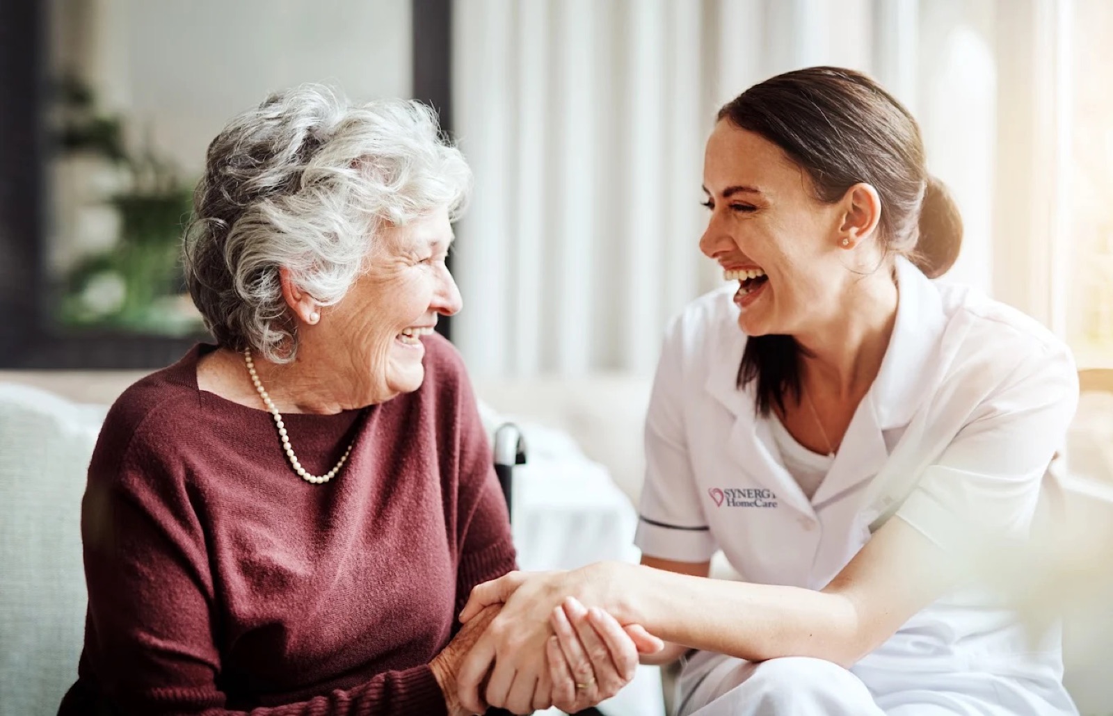 A SYNERGY HomeCare caregiver laughing with an older woman at home